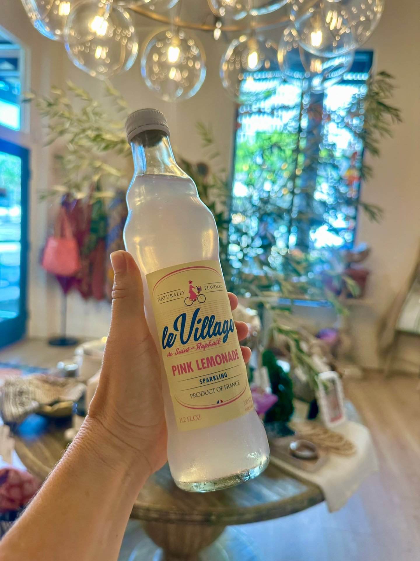A bottle of sparkling pink lemonade held up in the shop