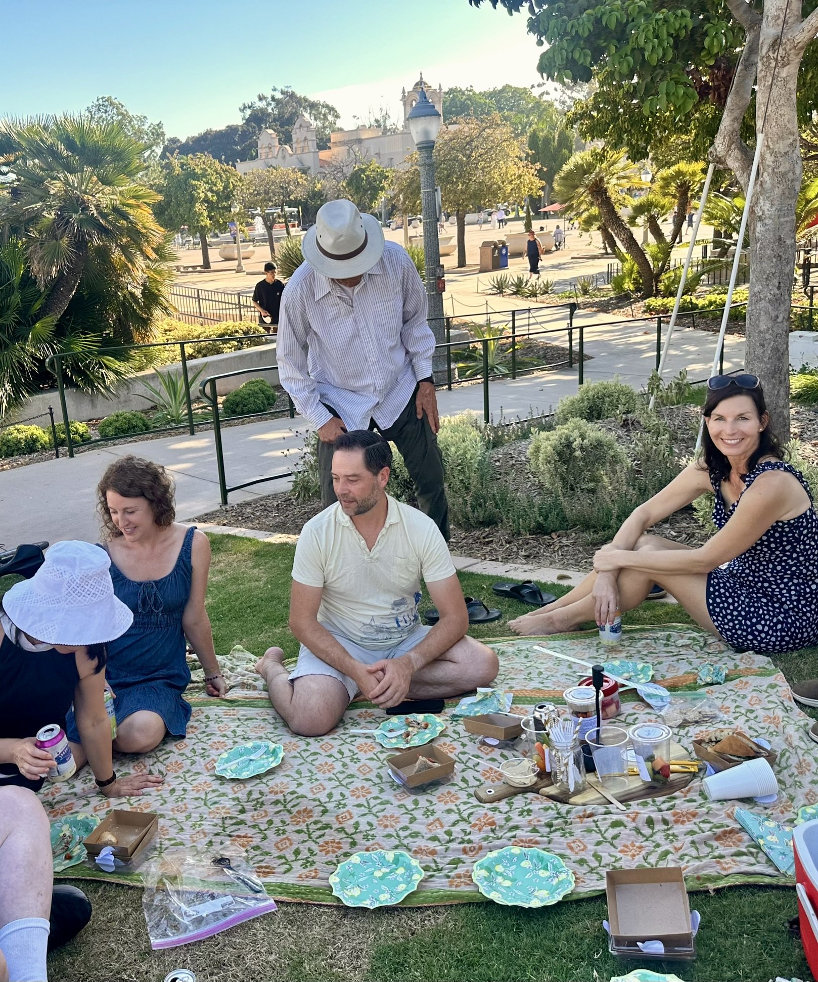 A group of friends gathered around a picnic on the lawn beside the Botanical Building